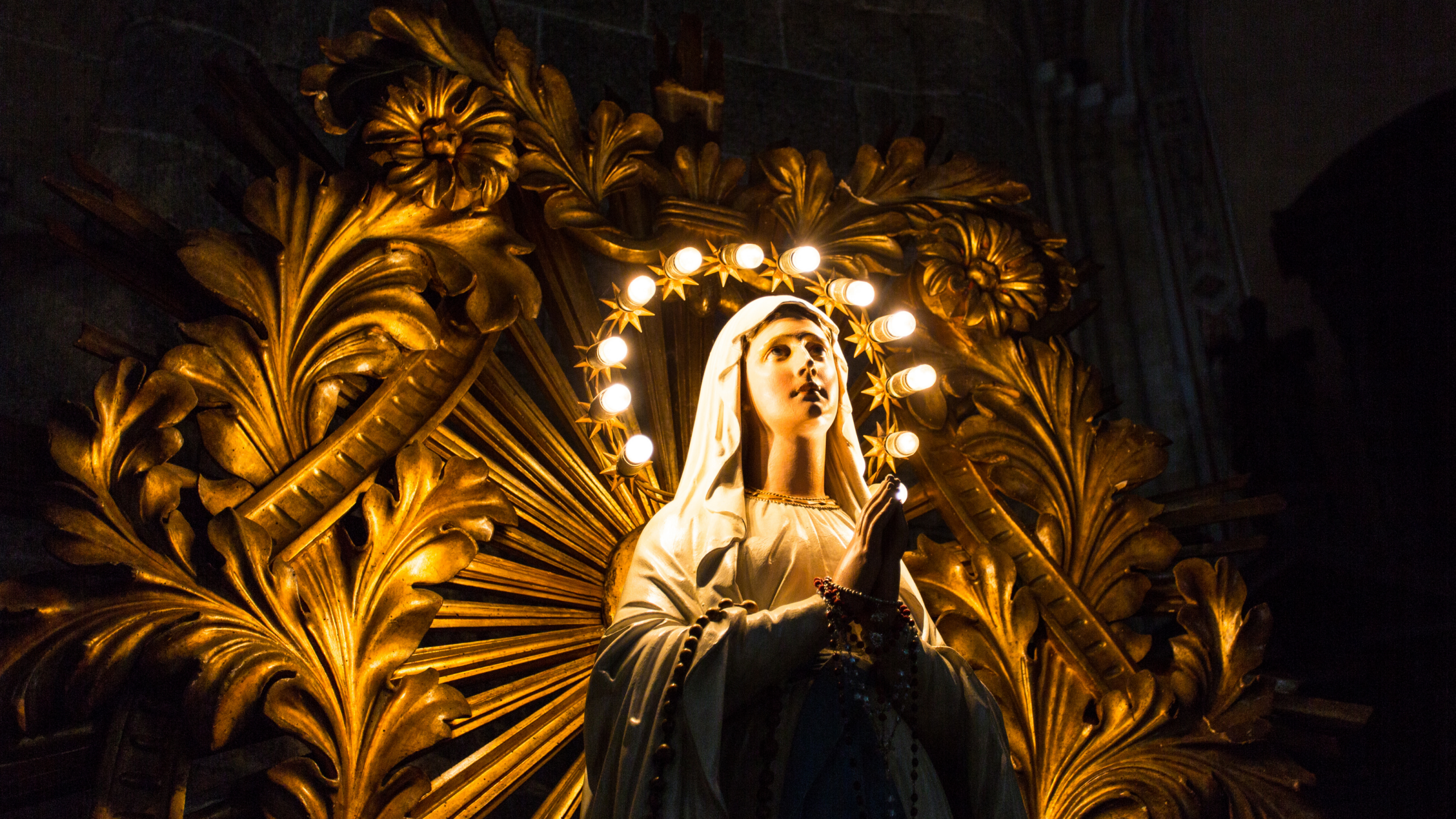 2 An ornate statue of the Virgin Mary with lights around her head in front of an elaborate gold sculpture