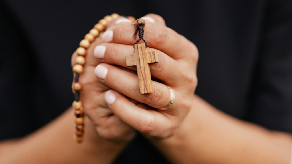 Hands holding a simple wooden rosary