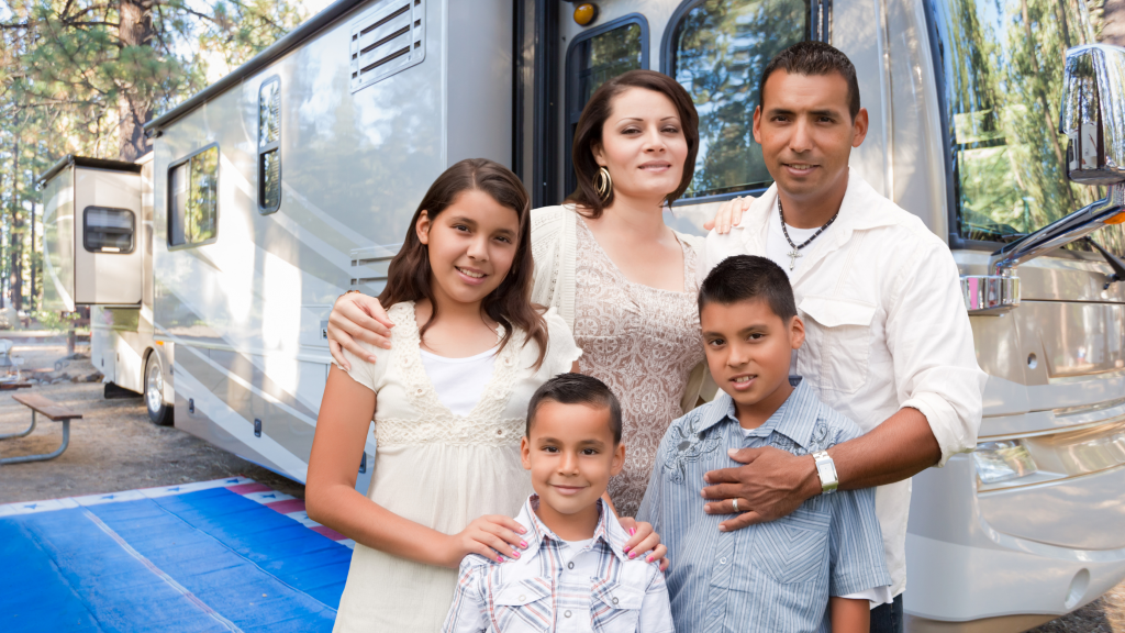 Two Latino parents and their three kids wearing nice clothes standing outside in front of an RV